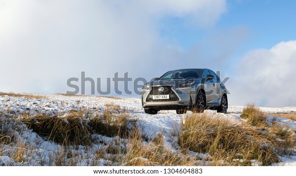 Brecon Beacons, UK: January\
30, 2019: A Lexus NX 300h F-Sport crossover hybrid car on the road\
side in snow and dangerous icy conditions. Panoramic with copy\
space.