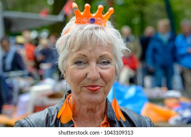 BREDA, NETHERLANDS - April 27, 2015: Unidentified Older Woman With Gray Hair, Orange Earrings And An Orange Colored Crown Poses For The Photographer; It Is King's Day In Breda.