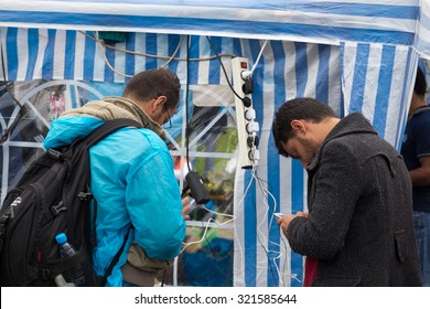 BREGANA, SLOVENIA: SEPTEMBER 19, 2015: Immigrants And Refugees From Middle East And North Africa At Bregana, State Border Between Slovenia And Croatia. Two Men Charging Their Cell Phones.