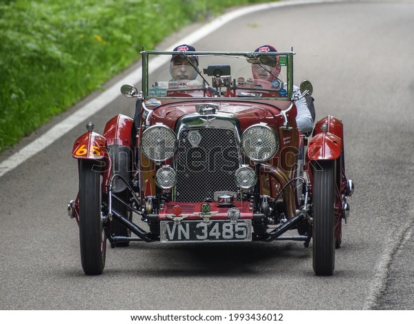 Brescia, Italy - June 16, 2021: A vintage 1931\
Aston Martin automobile rolls along Italian roads at the 2021 Mille\
Miglia, a 100-mile re-creation of the historic race from Brescia to\
Rome and back.