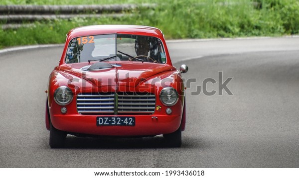 Brescia, Italy - June 16, 2021: A vintage 1950 Fiat\
Abarth automobile rolls along Italian roads at the 2021 Mille\
Miglia, a 100-mile re-creation of the historic race from Brescia to\
Rome and back.