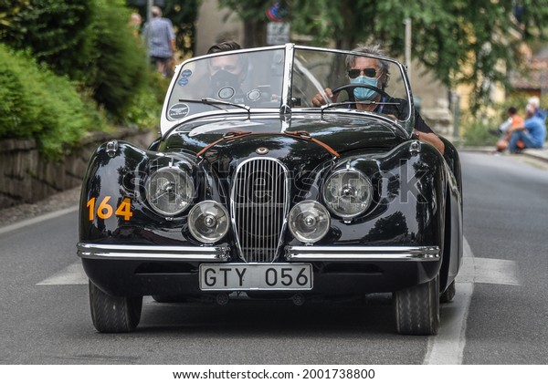 Brescia, Italy - June\
16, 2021: A 1950 Jaguar XK 120 in the opening miles of the 2021\
Mille Miglia, a 100-mile re-creation of the historic auto race from\
Brescia to Rome and\
back.