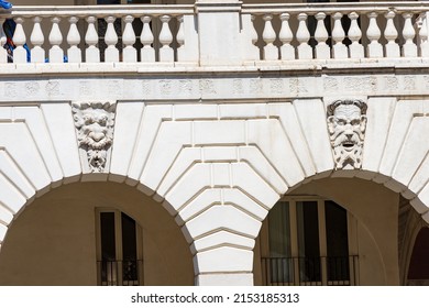 Brescia. Medieval Broletto Palace (Palazzo Broletto or Palazzo del Governo), XII-XXI century. Two white stone arches with keystones and grotesque human masks of gargoyles. Lombardy, Italy, Europe.
