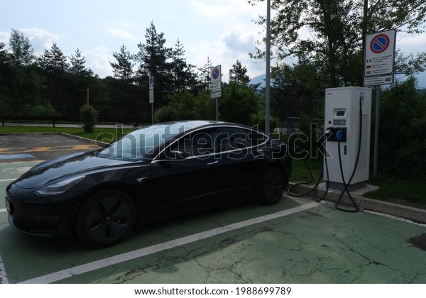 Bressanone, Bolzano, Italy\
- June 2, 2021: A static shot of a solid black Tesla Model 3 dual\
motor long range awd charging at the DC charging station in a sunny\
spring day