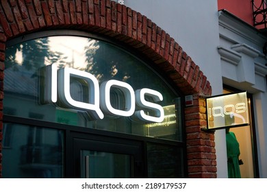 Brest, Belarus. Jun 2022. Sign IQOS Glowing In Evening. Neon Company Signboard IQOS On Shop Window. IQOS Of Philip Morris International - Boutique Of Heated Tobacco Smoking Devices. 