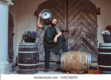 Brewer In Apron Holds Barrel With Craft Beer At Brewery Factory.