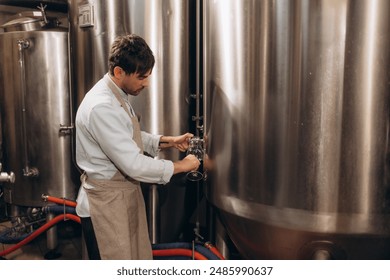 brewer at brewery pours beer into a glass from the tank for inspection - Powered by Shutterstock