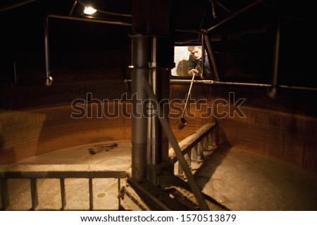 Brewer taking a beer sample from a lauter tun at brewery in Traunstein, Bavaria, Germany