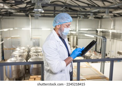 Brewer using a digital device at a beer plant (