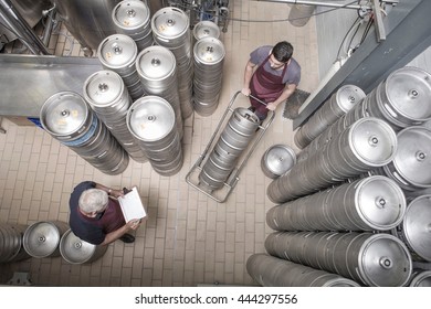 Brewers Moving Kegs In Brewery