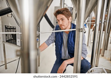 Brewery, production and man with steel in factory or distillery for winery, alcohol and drink manufacturing. Worker or winemaker checking container, metal or pipe of fermentation vessel for beer - Powered by Shutterstock