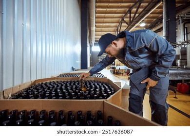 Brewery technologist carefully inspecting bottles in large shipment, ensuring each one meets the quality standards before distribution. Concept of beer, brewery, manufacture, quality control - Powered by Shutterstock