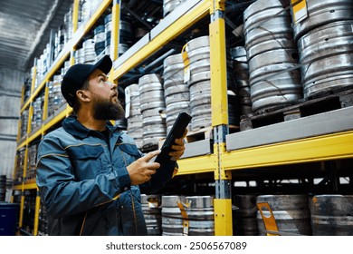 Brewery technologist inspecting rows of kegs in the storage area, getting ready for distribution. Maintaining accuracy in inventory tracking. Concept of beer, brewery, quality control - Powered by Shutterstock