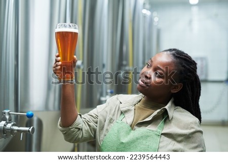 Brewery worker checking color of produced beer