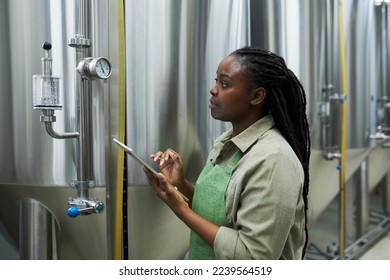 Brewery worker checking pressure and temperature in beer production equipment - Powered by Shutterstock