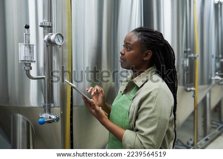 Brewery worker checking pressure and temperature in beer production equipment