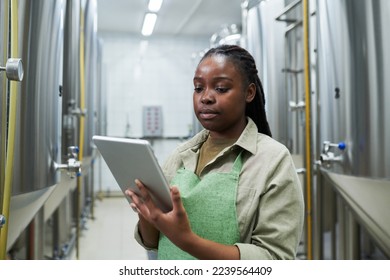 Brewery worker managing fermentation process via application on tablt computer - Powered by Shutterstock