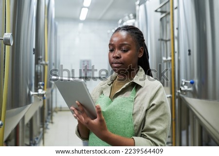 Brewery worker managing fermentation process via application on tablt computer