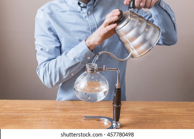 brewing coffee siphon. step by step cooking instructions. pouring siphon into the flask from the kettle of hot water - Powered by Shutterstock