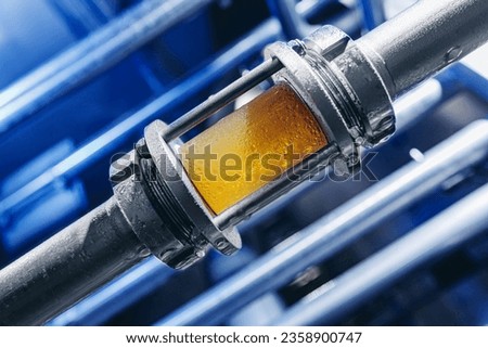 Brewing equipment for quality control, sight glass full of golden beer on stainless steel pipe. Concept brewery food industry.