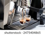 Brewing espresso in to glass cups silver coffee espresso machine white and clean interior. Barista working with coffee machine and making espresso coffee, speciality coffee black arabica