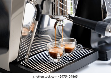 Brewing espresso in to glass cups silver coffee espresso machine white and clean interior. Barista working with coffee machine and making espresso coffee, speciality coffee black arabica