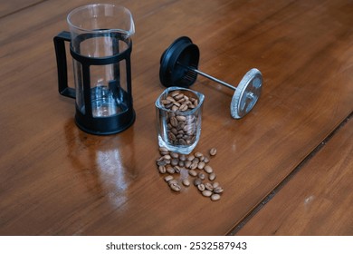 Brewing method French press coffee maker, with french press and glass of coffee beans on the wooden table, making coffee homemade. - Powered by Shutterstock