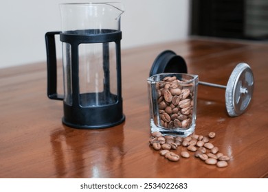 Brewing method French press coffee maker, with french press and glass of coffee beans on the wooden table, making coffee homemade. - Powered by Shutterstock