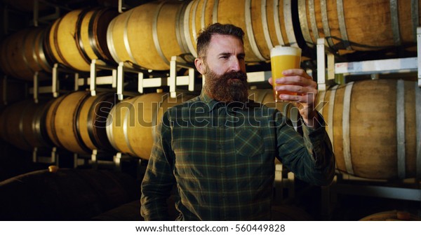 a brewmaster expert checks the quality of the\
freshly tapped beer from wooden barrels formerly used for flavour\
the wine or beer.