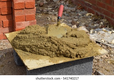 Brick Adhesive On A Table With A Brick Jointer; Construction Area In The Background