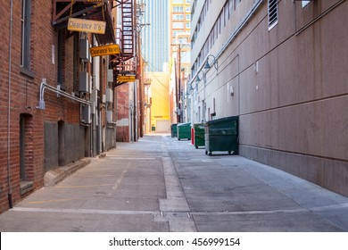 Brick Alleyway With Dumpsters And Fire Escape And Copy Space.