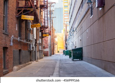 Brick Alleyway With Dumpsters And Fire Escape And Copy Space.