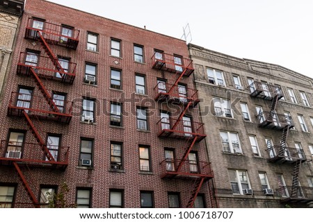 Brick apartment condo building exterior architecture in Fordham Heights center, Bronx, NYC, Manhattan, New York City with fire escapes, windows, ac units in evening