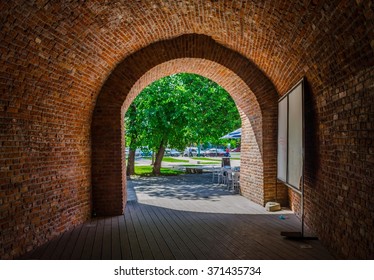 a brick arch with a green tree behind it.