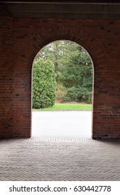 Brick arch with park in the background and herringbone tiled floor in the foreground at Bispebjerg Hospital in Copenhagen, Denmark