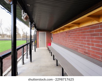 Brick baseball dugout with concrete floor, benches and protective netting.
 - Powered by Shutterstock