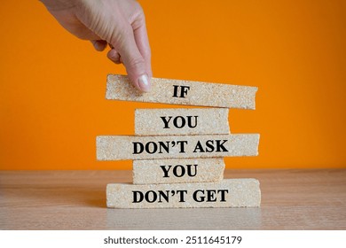 Brick blocks with words If you don't ask, you don't get on the wooden table. Beautiful orange background, businessman hand. Motivational and inspirational quotes for students. Copy space. - Powered by Shutterstock