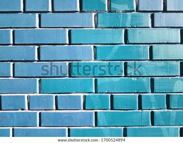 Brick blue wall with glossy bricks. Wall of a brick\
house with contrasting seams. Blue Kerpichi for design and\
background in horizontal orientation. The blue wall is divided into\
two parts
