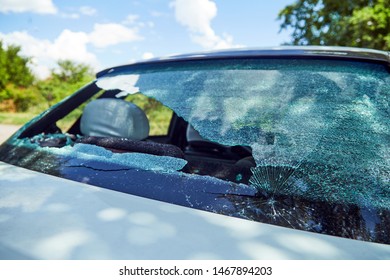 Brick In A Broken Rear Window Of A Car.