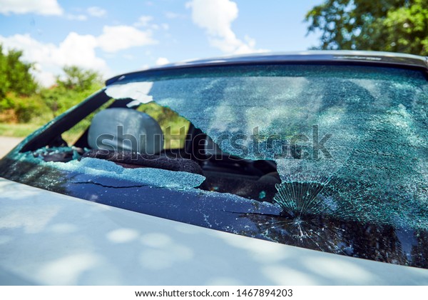 Brick in a broken rear\
window of a car.