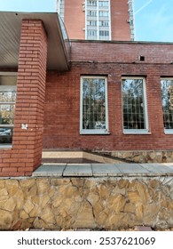 brick building with alternating red and gray patterns, showcasing windows and air conditioning units. The close-up view highlights the clean and functional design typical of modern city architecture.