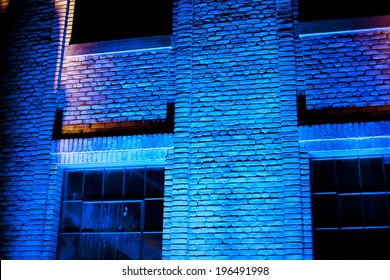 A brick building with neon lights reflecting off of it.