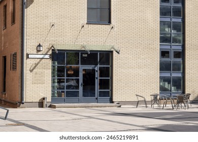 A brick building prominently displays the letter r on its facade, standing in an urban setting with a paved road surface, cityscape, and shades around - Powered by Shutterstock