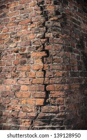 Brick building structure with a large crack running down the centre.