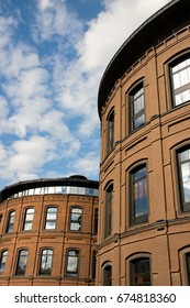 A brick building with windows reflecting clouds and sky.
