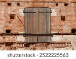 A brick building with a wooden door. The door is wooden and has a metal hinge