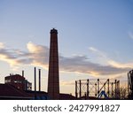 Brick chimney against the cloudy dusk sky. City afterglow silhouette. Technopolis, Athens, Greece