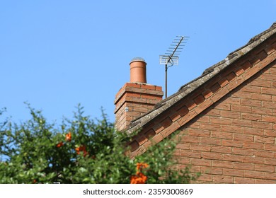 Brick chimney on a modern house with a tv aerial at the side