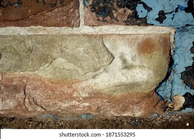 Brick Exposed Under Chipped Plaster Covered With Old Blue Paint