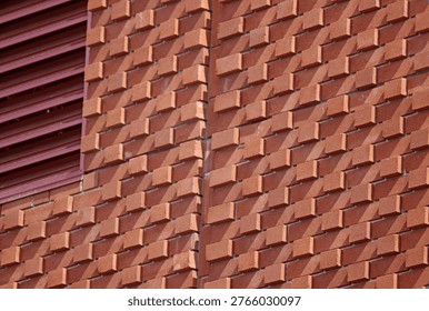 Brick facade with geometric relief pattern and red louvre ventilation detail